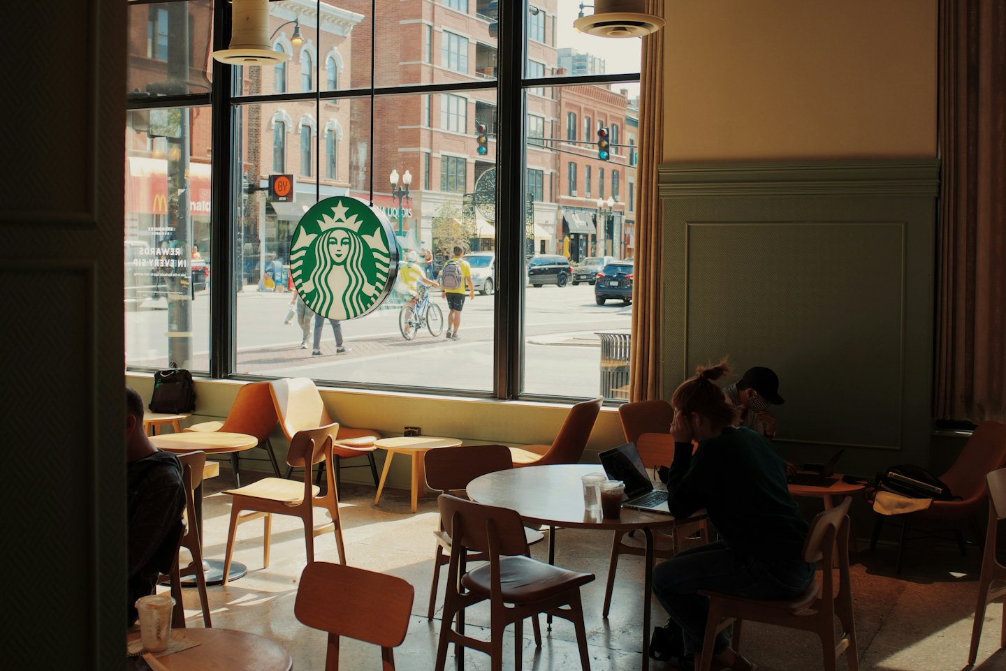Woman working on laptop at coffee shop table.